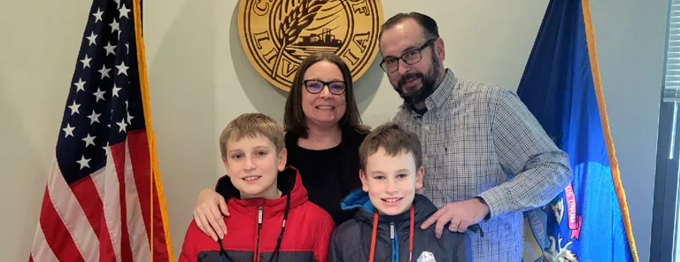 Robb Drzewicki with his wife and two sons in front of the City of Livonia seal